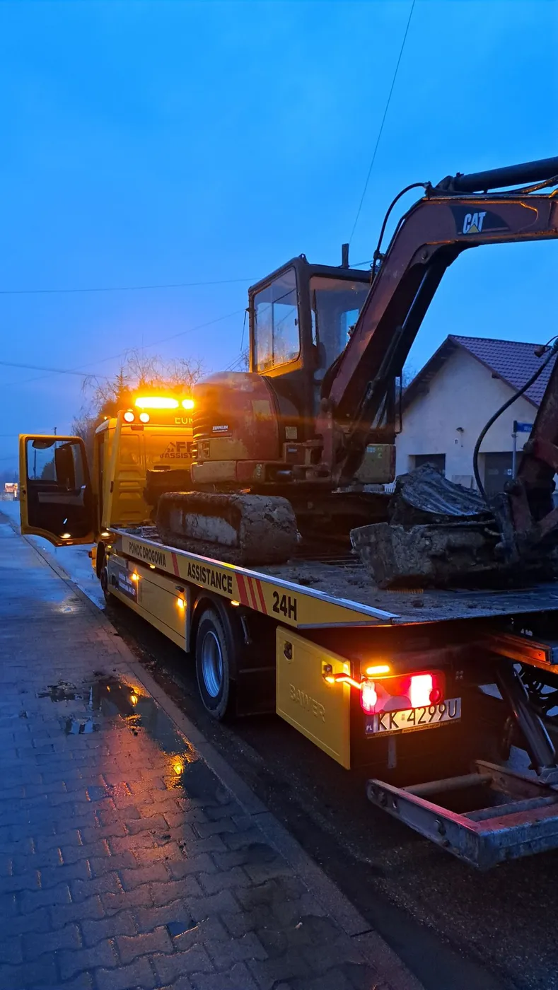 Transport koparki CAT na lawecie o zmierzchu – Kraków